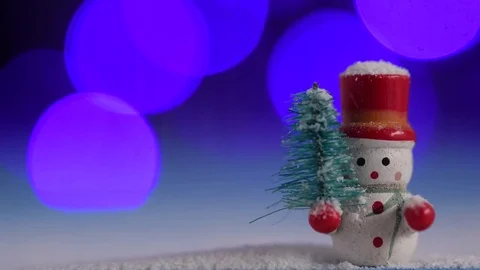 Cute Snowman holding a pine tree, and snowfall, bokeh background Stock Footage 84958468