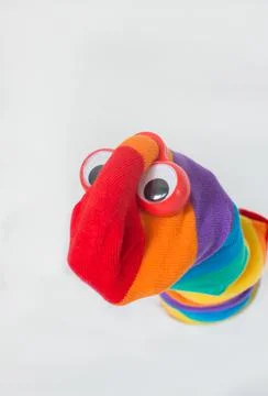 Cute sock puppet with rainbow flag sock and plastic red eyes. White backgroun Stock Photos