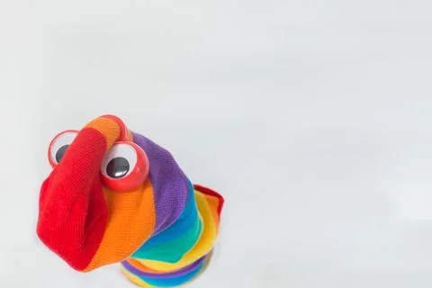 Cute sock puppet with rainbow flag sock and plastic red eyes. White backgroun Stock Photos