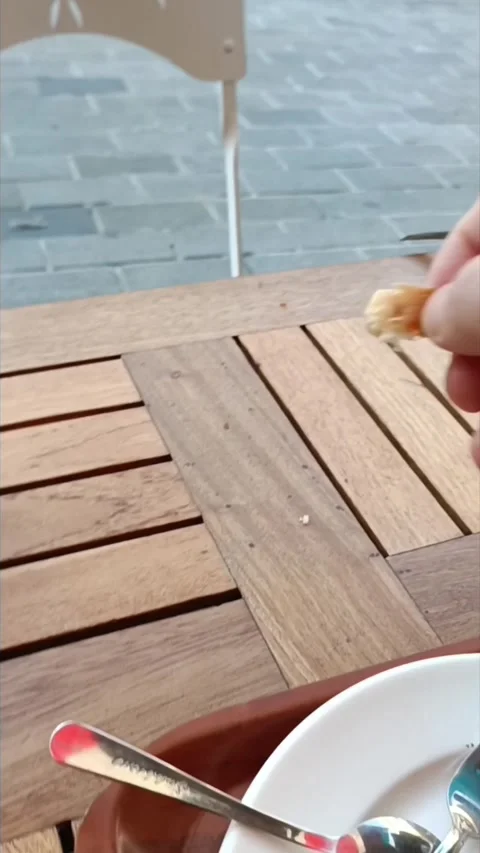 ​Cute sparrow eating bread crumbs from a man's hand at a cafe table Video stock 335849753