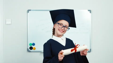Cute student 7-8 years graduate in the mantle and hat holding diploma Video stock 64859250