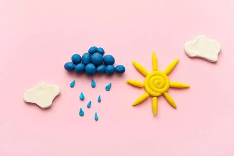 Cute sun with clouds and rain drops made of plasticine on pink background Stock Photos