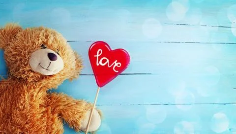 Cute Teddy Bear and Reda Candy Heart on Wood Background Stock Photos
