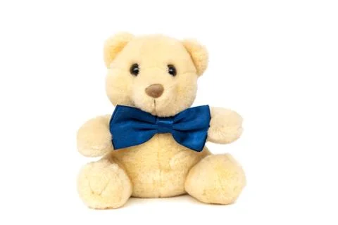 Cute teddy bear with blue bow tie sitting at white wall Stock Photos