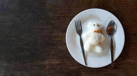 Cute teddy bear shape made from white rice with spoon and fork on dish Stock Photos