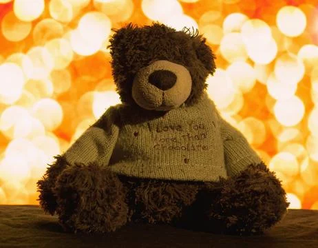 Cute teddy bear sitting on the background of orange lights Stock-Fotos