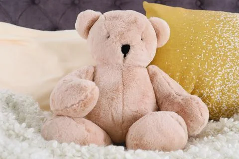 Cute teddy bear sitting on bed indoors Stock Photos