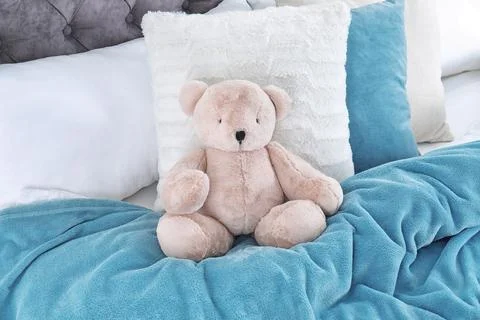 Cute teddy bear sitting on bed indoors Stock Photos