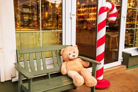 Cute Teddy Bear Sitting on a Bench Beside a Giant Candy Cane During the Festi Stock Photos
