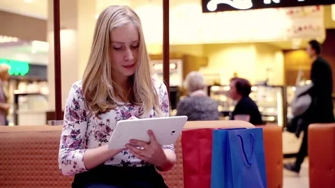 Cute teenage using tablet computer at shopping mall Stock Footage 87475064