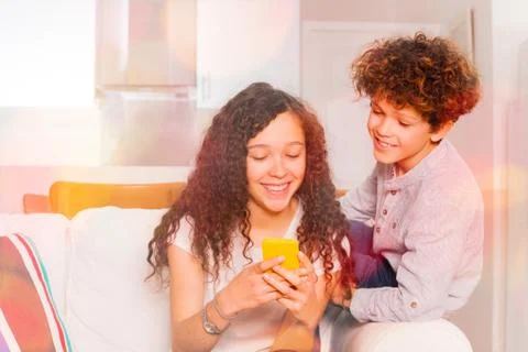 Cute teens chatting using cell phone indoors Stock Photos