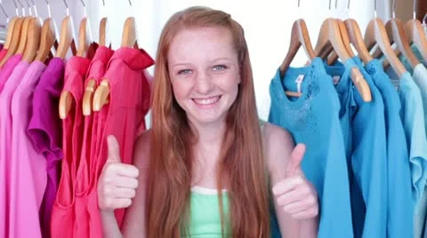 Cute Teen/Tween Gives Thumbs Up Sign from Clothes Rack Stock Footage 12540237