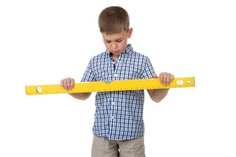 A cute thoughtful builder assistant in a blue checkered shirt holds a big yellow Stock Photos