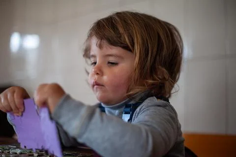 Cute three-year-old solving a puzzle with focus and joy Foto stock