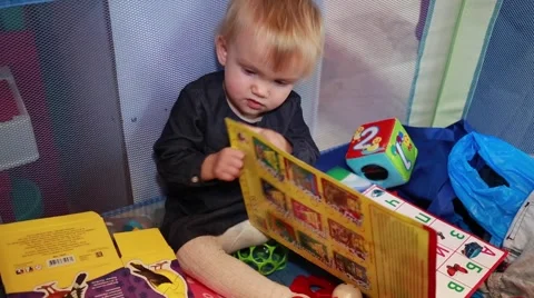 Cute toddle opening big ABC book, turning pages, learning, looking at camera Stock Footage 58074359