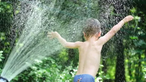 Cute toddler blond boy playing with garden sprinkler on summer hot day. Stock Footage 134194006