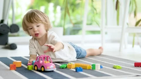Cute toddler boy playing with lego blocks construction set on the floor at home Stock Footage 245842014