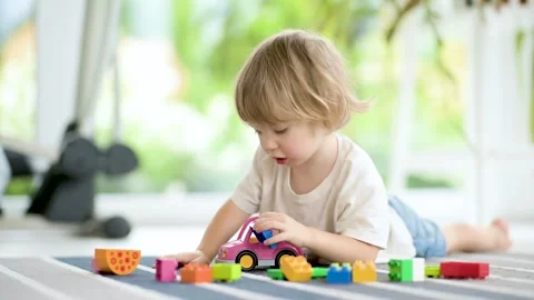 Cute toddler boy playing with plastic blocks construction set on floor at home 스톡 동영상 304680375