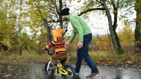 Cute toddler boy practicing cycling. Father teaches his little kid to ride bike Stock Footage 118268760