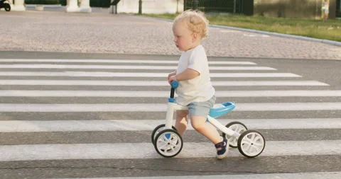 Cute toddler boy rides small bicycle on empty road crosswalk Stockbeeldmateriaal 201377477