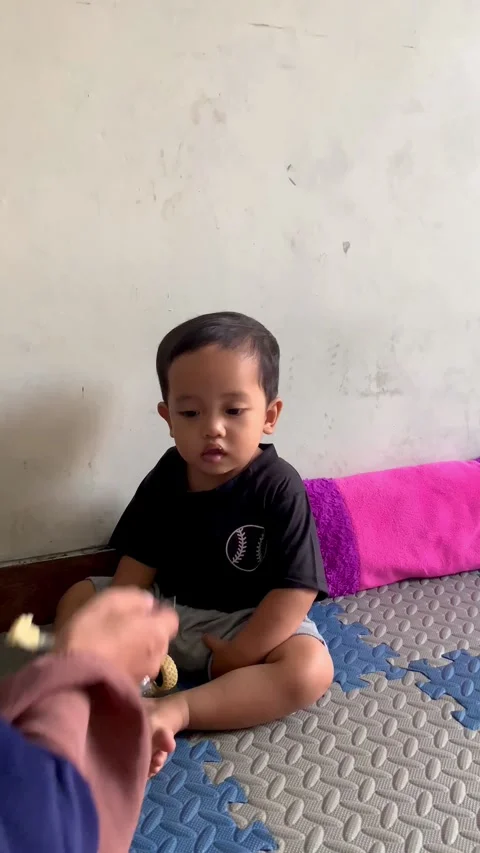 A cute toddler boy sitting on a play mat and playing with a toy monster truck Stock Footage 336843540