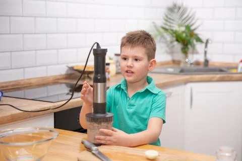 Cute toddler boy using hand blender to make minced meat. Preparing meal in th Stock Photos