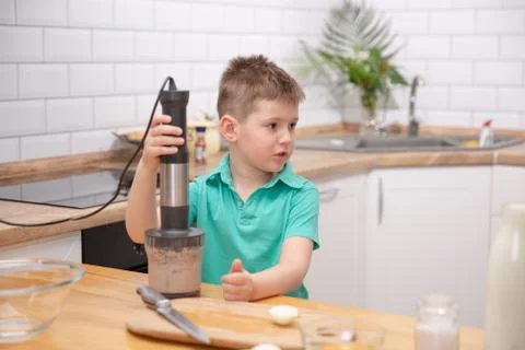 Cute toddler boy using hand blender to make minced meat. Preparing meal in th Stock Photos