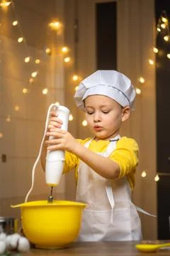 Cute toddler boy using hand blender to dough to cake . Preparing healthy meal in Stock-Fotos