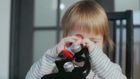 Cute toddler boy using a toy baby microscope. Educational toys for children. Stock Footage 151592922