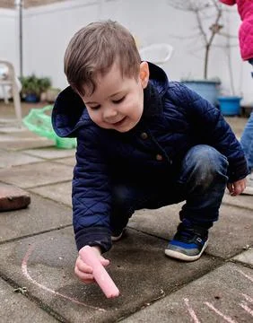 Cute toddler is drawing in the backyard Fotos Stock