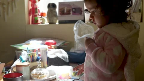 Cute toddler girl eats something using spoon, holding it close to their lip.. Stock Footage 303495381