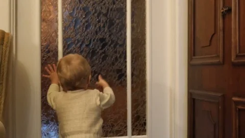 Cute toddler knocking into the door in the flat Stock Footage 83923372