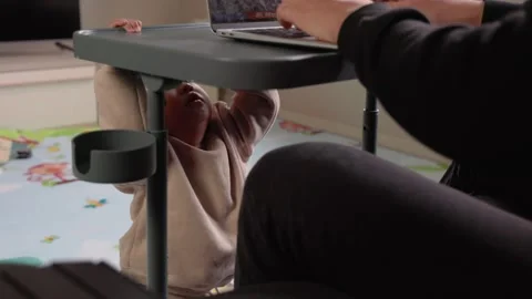 A cute toddler playing on the floor while his father works on a laptop Stock Footage 244825996