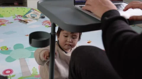 A cute toddler playing on the floor while his father works on a laptop Stock Footage 244827514