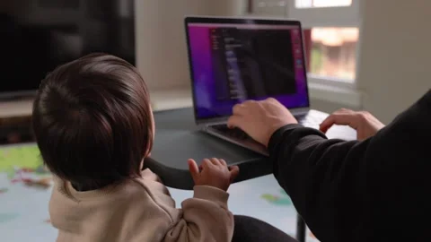 A cute toddler playing on the floor while his father works on a laptop Stock Footage 244828889