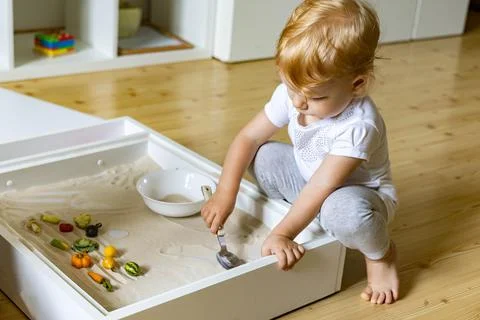 Cute toddler playing self development home kinetic sandbox use Maria Montessori Stock Photos