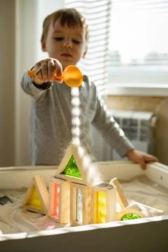 Cute toddler playing self development home kinetic sandbox use Maria Montessori Stock Photos