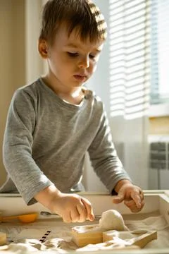 Cute toddler playing self development home kinetic sandbox use Maria Montessori Stock Photos