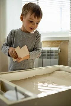 Cute toddler playing self development home kinetic sandbox use Maria Montessori Stock Photos