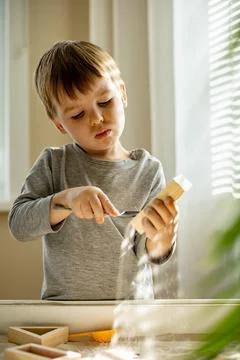 Cute toddler playing self development home kinetic sandbox use Maria Montessori Stock Photos