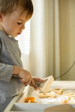 Cute toddler playing self development home kinetic sandbox use Maria Montessori Stock Photos