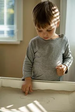 Cute toddler playing self development home kinetic sandbox use Maria Montessori Stock Photos