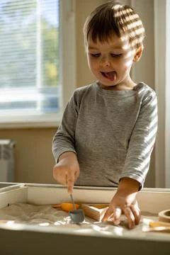 Cute toddler playing self development home kinetic sandbox use Maria Montessori Foto stock
