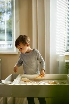 Cute toddler playing self development home kinetic sandbox use Maria Montessori Foto stock