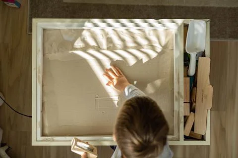 Cute toddler playing self development home kinetic sandbox use Maria Montessori Foto stock