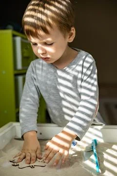 Cute toddler playing self development home kinetic sandbox use Maria Montessori Stock Photos