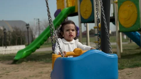 Cute toddler Pushing an Empty Blue Swing at the Playground Stock Footage 306732545