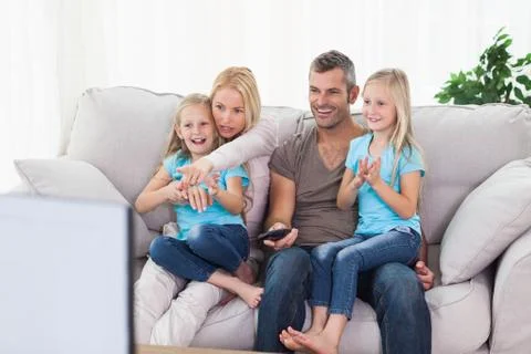 Cute twins and parents watching television Stock Photos