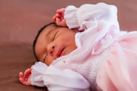 Cute two weeks old newborn baby girl wearing soft pink knit clothes, sleeping Stock Photos