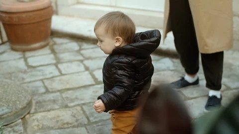 Cute Two-year-old boy in a black jacket walks an empty street with his mother 스톡 동영상 127039103